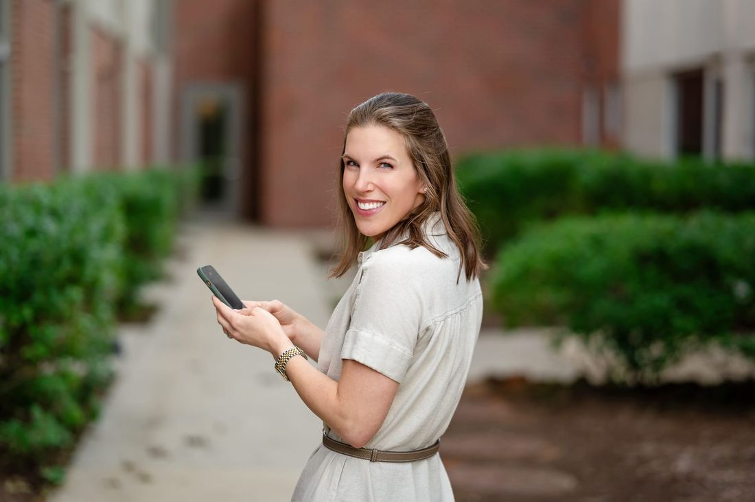 Lauren smiling over her shoulder while holding her phone